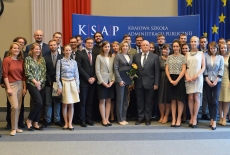 Zdjęcie grupowe uczestników uroczystości, na tle flag Polski i UE oraz baneru KSAP.