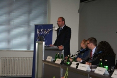 Pan stoi na mównicy i przemawia siedzą prowadzący konferecję